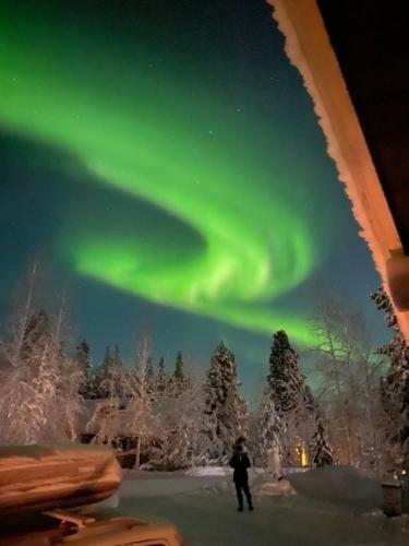 an image of a person standing under the aurora borealis at Liirakka Levi in Levi