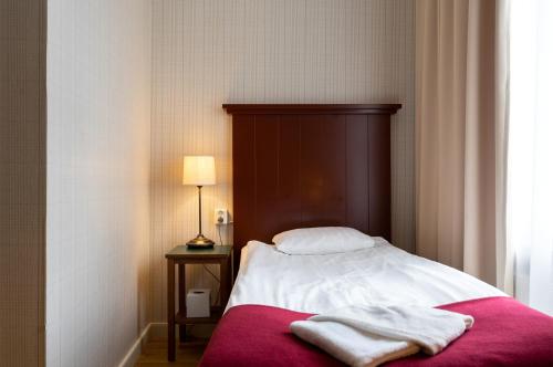 a bed with two towels on it in a room at Hotel Bishops Arms Kristianstad in Kristianstad