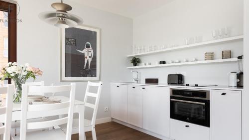 a kitchen with white cabinets and a table and chairs at Flatbook - City Center SPA Apartments Motlawa in Gdańsk