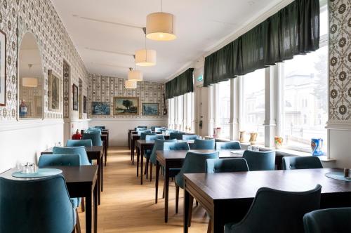 a dining room with tables and blue chairs at Hotel Bishops Arms Kristianstad in Kristianstad