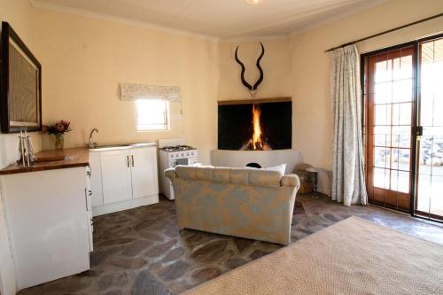 a living room with a couch and a kitchen with a fireplace at Wild Olive Cottage in Graaff-Reinet