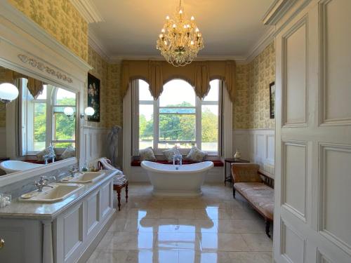 baño con bañera, 2 lavabos y lámpara de araña en Rossington Hall en Doncaster