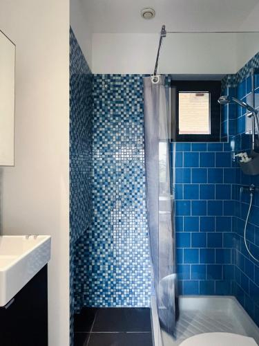 La salle de bains est pourvue d'une douche carrelée de bleu et d'un lavabo. dans l'établissement Calme, mer et montagne Anglet, à Anglet