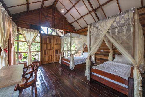 2 łóżka w pokoju z drewnianymi podłogami i oknami w obiekcie Borneo Sepilok Rainforest Resort w mieście Sepilok