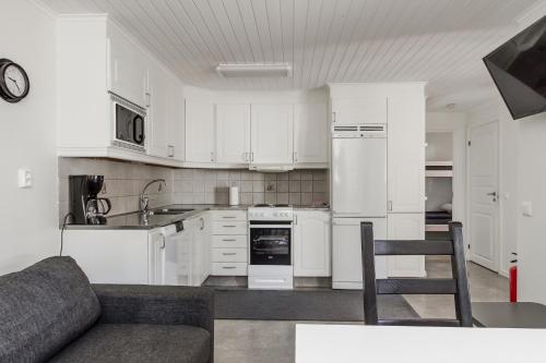 a kitchen with white cabinets and a couch in a room at Karlstad Swecamp Bomstadbaden in Karlstad