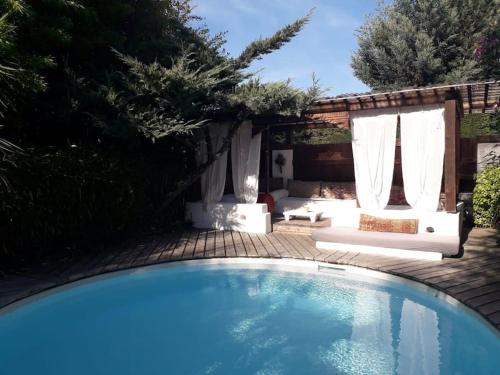 einen Pool im Garten mit weißen Vorhängen und einer Terrasse in der Unterkunft maison de vacances in La Teste-de-Buch