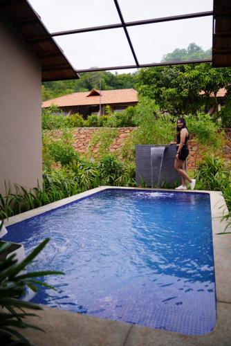 a woman in a bikini walking next to a swimming pool at Ravishing Retreat Resort in Rāmanagaram