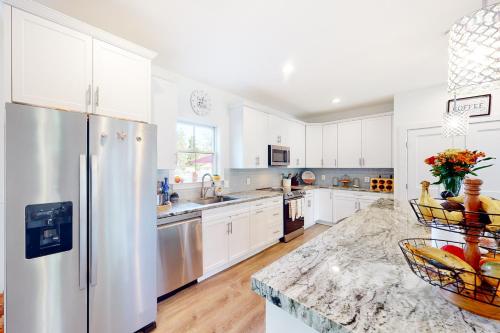 a kitchen with white cabinets and a stainless steel refrigerator at Pasadena Retreat in Glen Burnie