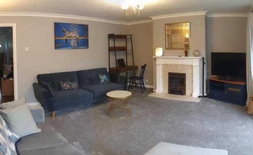a living room with a blue couch and a fireplace at Pinewood Studios, Iver near Heathrow and Windsor XL 75sqm 2 King Bed Flat with 2 Parking Spaces in Buckinghamshire