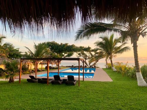 un complejo con una piscina con sillas y palmeras en Mar De Estrellas - Hotel en Costa Esmeralda