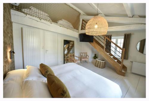 a bedroom with a large white bed and a staircase at La Maison Rose, chaleureuse et luxueuse in Roanne