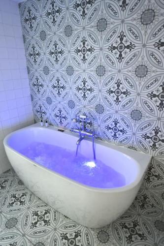La salle de bains est pourvue d'une baignoire avec de l'eau bleue. dans l'établissement La Maison Rose, chaleureuse et luxueuse, à Roanne