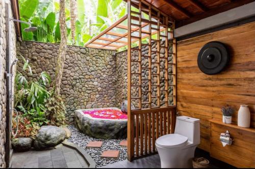 a bathroom with a toilet and a stone wall at Govinda Villas in Penginyahan