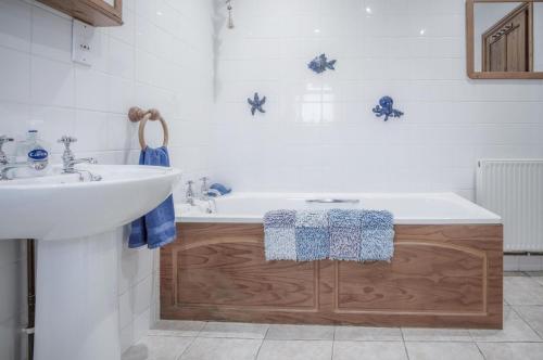 a bathroom with a white tub and a sink at Fferm-Llong Cottage Ship Farm - 2 Bedroom -Rhossili in Rhossili