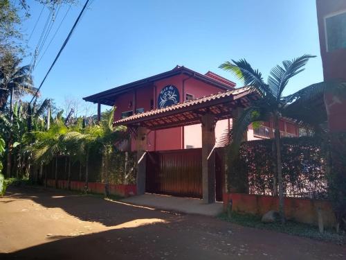 Una casa roja con un reloj encima. en Toca do Guaiamum I, en Ubatuba