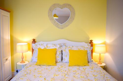 um quarto com uma cama com almofadas amarelas e um espelho em Avocet - Suffolk Coastal Escapes em Pakefield