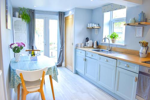 a blue kitchen with a table and a sink at Avocet - Suffolk Coastal Escapes in Pakefield