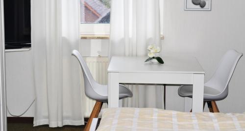 een witte tafel en 2 stoelen in een slaapkamer bij Hotel Pension Petra in Bad Zwischenahn