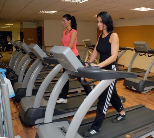 two women walking on a treadmill in a gym at Sport Hotel in Debrecen