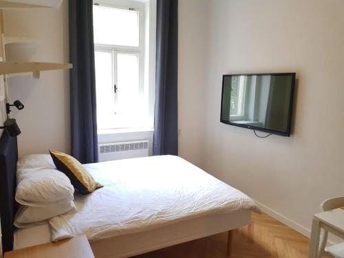 Cette chambre comprend un lit et une télévision murale. dans l'établissement Stylish studio apartment by Namesti Miru, à Prague