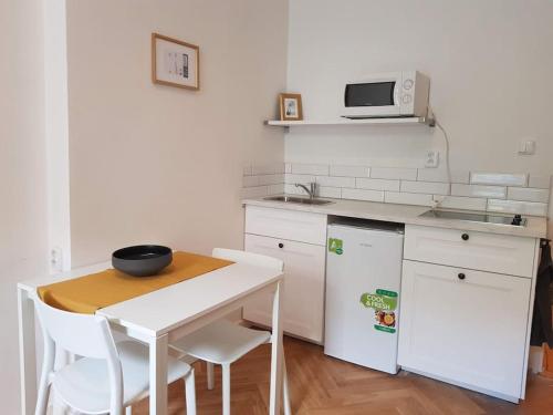 - une cuisine blanche avec une table et un four micro-ondes dans l'établissement Stylish studio apartment by Namesti Miru, à Prague