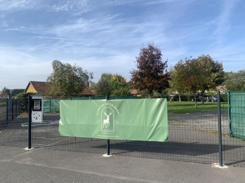a fence with a green sign on it at Camping De La Sarre in Abreschviller