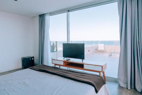 a bedroom with a bed and a desk with a television at Pinamar Beach Resort in Pinamar