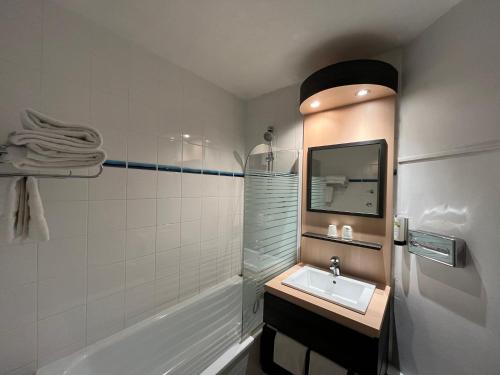 y baño con lavabo y bañera. en Hôtel Le Néron - Logis, en Fontanil-Cornillon