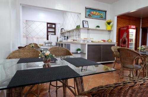 a dining room with tables and chairs and a kitchen at Pousada Navegantes in Navegantes