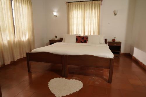 a bedroom with a large bed with white sheets at Carpe DiemStay in Kushālnagar