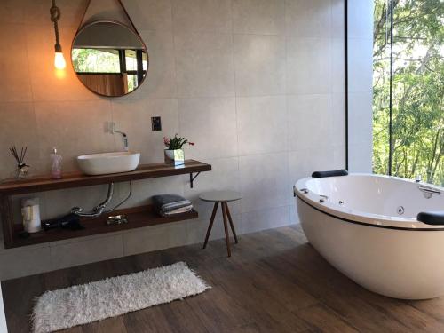 a bathroom with a tub and a sink and a mirror at Pousada Sitio Raizes in Siderópolis