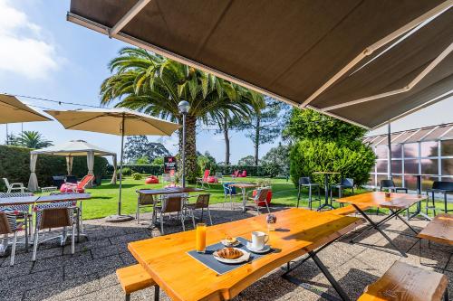 a patio with tables and chairs and umbrellas at Hotel ibis Porto Gaia in Vila Nova de Gaia