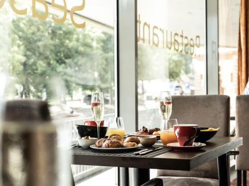 a table with plates of food and glasses of wine at Falkensteiner Hotel Bratislava in Bratislava