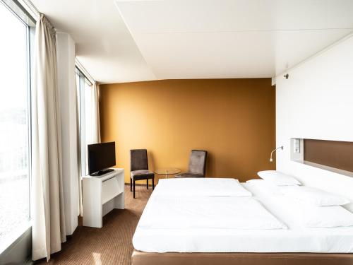 a hotel room with two beds and a tv at Falkensteiner Hotel Bratislava in Bratislava