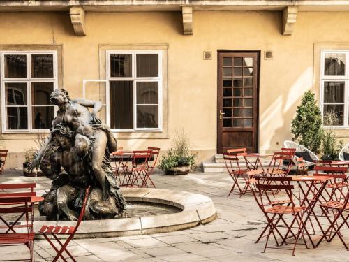 a statue in front of a building with tables and chairs at Falkensteiner Hotel Bratislava in Bratislava