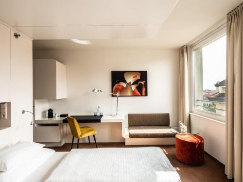 a bedroom with a bed and a desk and a chair at Falkensteiner Hotel Bratislava in Bratislava
