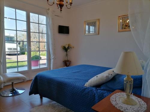 une chambre avec un lit bleu et une fenêtre dans l'établissement Villa grand communal, piscine, 18km de Bordeaux, à Ludon-Médoc
