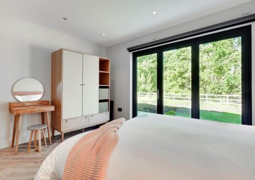 a bedroom with a bed and a desk and a window at Daisys Barn in Mattishall