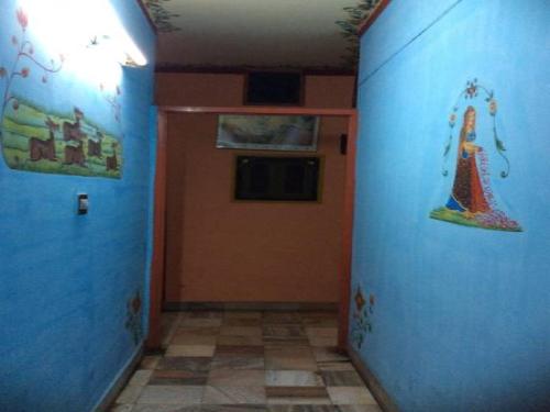a hallway with a door with paintings on the walls at Govind Hotel in Jodhpur