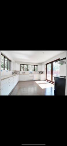 a large kitchen with white counters and windows at Mansion 8 bedrooms in Private Gated Ave Huge garden Hot tub FREE SAUNA up to 23 in Luton