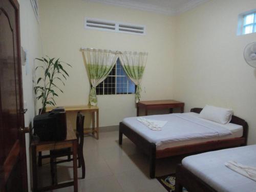 a room with two beds and a tv and a window at Visal Sak Guesthouse in Kep