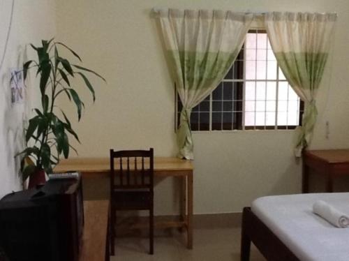 a bedroom with a table and a window with a plant at Visal Sak Guesthouse in Kep