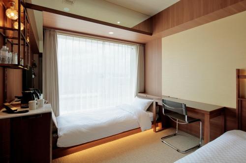a bedroom with a bed and a desk and a window at Candeo Hotel Utsunomiya in Utsunomiya