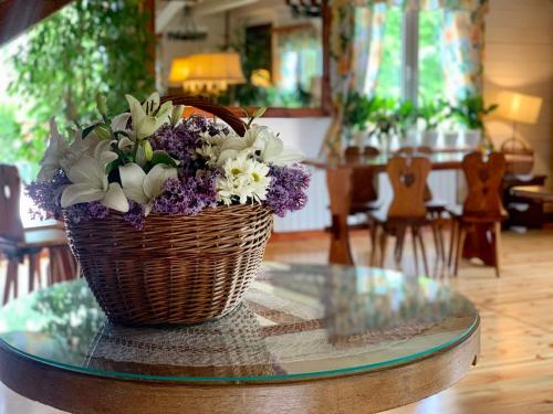 a basket of flowers sitting on a glass table at Karczma Leśniczanka in Wielbark