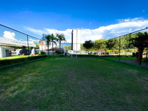 a tennis court with a fence and a field at Hotel Rainha do Brasil in Aparecida