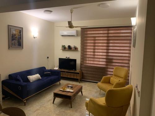 a living room with a blue couch and two chairs at Dreams Apartments شقق الاحلام in Baghdad