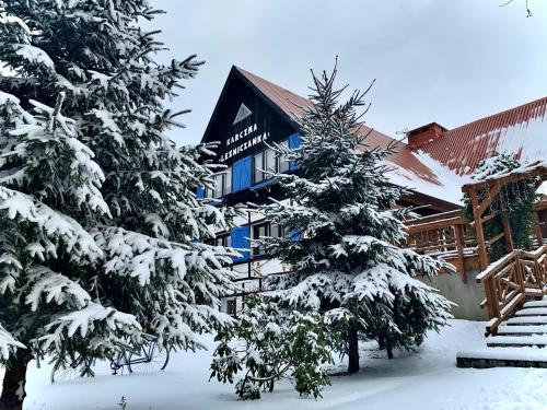 a building with snow covered trees in front of it at Karczma Leśniczanka in Wielbark