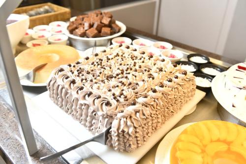 a chocolate cake sitting on a counter with other desserts at Hotel Rainha do Brasil in Aparecida