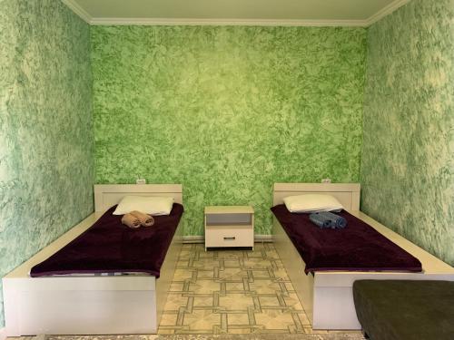 zwei Betten in einem Zimmer mit grünen Wänden in der Unterkunft Nlife hotel in Qapschaghai