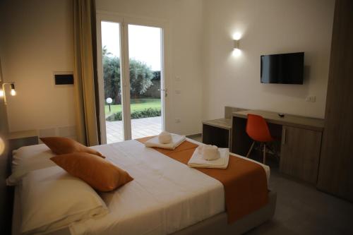 a hotel room with a bed and a desk and a window at Oasi Guzzetta Hotel in Marsala